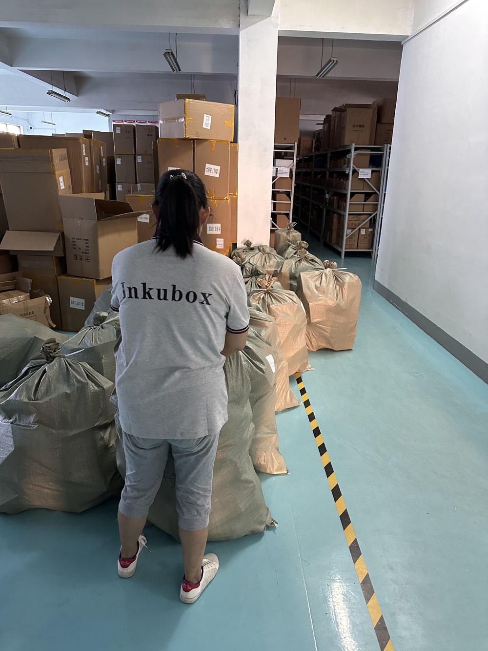 les colis dans la zone de départ avec une employée inkubox de dos